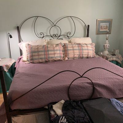 Sale Photo Thumbnail #83: Wrought iron king size bed frame featuring scrollwork detailing, complete with bedding and nightstands.
