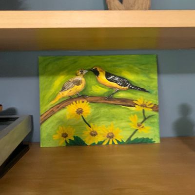 Sale Photo Thumbnail #73: Original canvas painting depicting two yellow birds perched on a branch above bright yellow flowers, displayed on a wooden shelf.