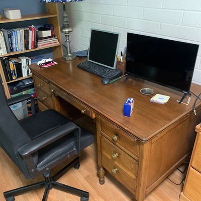 Sale Photo Thumbnail #63: Traditional wooden double-pedestal executive desk featuring turned legs and brass hardware, paired with a modern black mesh office chair.