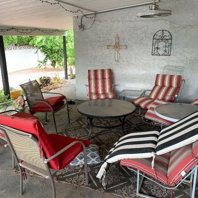 Sale Photo Thumbnail #40: Outdoor patio furniture set featuring metal lounge chairs with red and red-and-white striped cushions, paired with a glass-top coffee table and an outdoor rug.