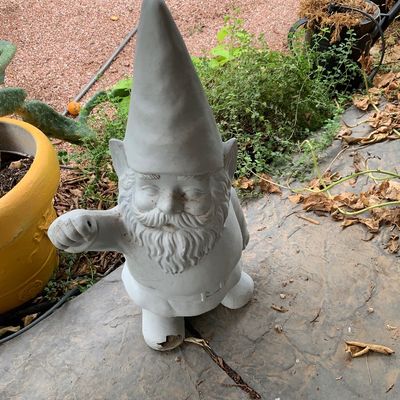 Sale Photo Thumbnail #42: Cast concrete or resin garden gnome statue with a pointed hat and full beard, showing minor wear and a chip on the base.