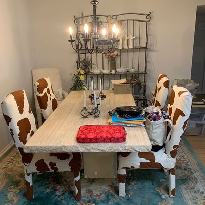 Sale Photo Thumbnail #9: Contemporary dining room set featuring a thick stone-top dining table surrounded by high-back chairs with faux cowhide slipcovers, set beneath a wrought iron chandelier.