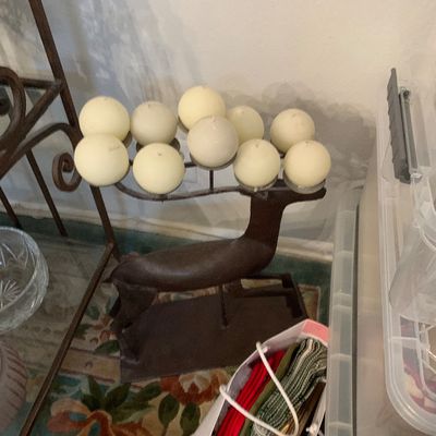 Sale Photo Thumbnail #80: Cast iron deer-shaped multi-candle holder holding spherical cream-colored candles, displayed on a patterned rug.