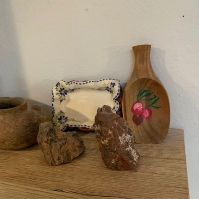Sale Photo Thumbnail #75: Collection of decorative items including two mineral rock specimens, a hand-painted wooden scoop with cherry motif, a vintage floral ceramic dish, and a small earthenware pot on a shelf.