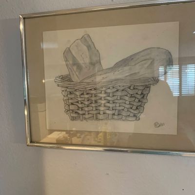 Sale Photo Thumbnail #77: Framed pencil sketch of bread in a woven basket, signed in the bottom right corner, set in a silver metal frame.
