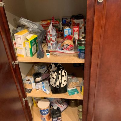 Sale Photo Thumbnail #21: Open wooden pantry cabinet filled with various household food items, canned goods, boxed snacks, and a black and white polka dot handbag.