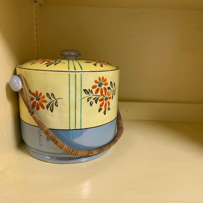 Sale Photo Thumbnail #34: Vintage Japanese lusterware cookie jar featuring hand-painted orange floral motifs, a two-tone yellow and blue glaze, and a wrapped rattan handle.