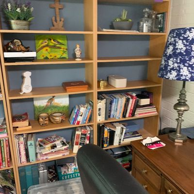 Sale Photo Thumbnail #67: Pair of light wood bookcases filled with books, small artwork, and decorative objects, paired with a blue floral lampshade on a metal base.