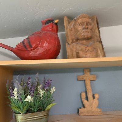 Sale Photo Thumbnail #72: Hand-carved wooden decor display including a painted red cardinal figure, a carved wooden bust, a potted artificial lavender arrangement, and a carved wooden crucifix.