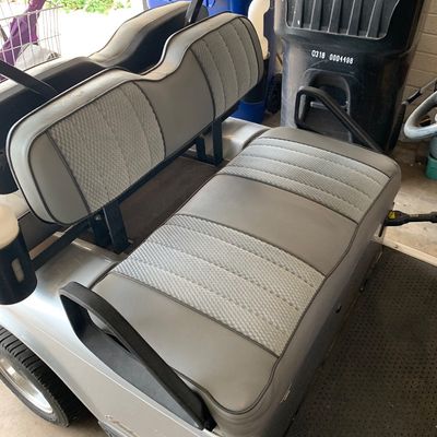 Sale Photo Thumbnail #49: Golf cart with two-tone grey vinyl and textured fabric upholstery, parked indoors near trash bins.