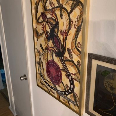 Sale Photo Thumbnail #82: Framed Indigenous Australian style bark-inspired art print featuring a stylized lizard motif, presented in a thin gold metal frame.