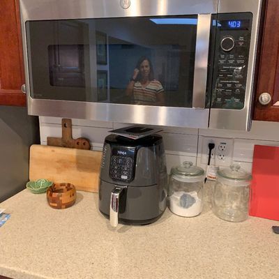 Sale Photo Thumbnail #17: A modern GE Profile stainless steel over-the-range microwave and a Ninja air fryer positioned on a kitchen countertop alongside glass storage jars and wooden cutting boards.