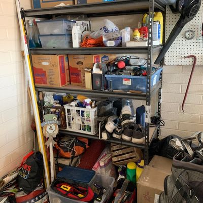 Sale Photo Thumbnail #53: Tall metal shelving unit filled with organized garage and household supplies, including plastic storage bins, moving boxes, cleaning fluids, tools, and athletic shoes.