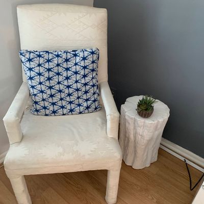 Sale Photo Thumbnail #6: Fully upholstered cream armchair with subtle geometric jacquard patterning and a blue shibori throw pillow, paired with a white faux tree stump side table.