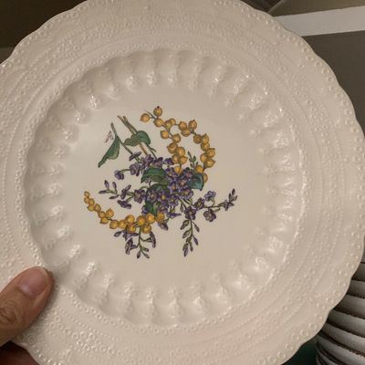 Sale Photo Thumbnail #113: Vintage white ceramic plate featuring a floral central design of yellow and purple wildflowers with an embossed scalloped rim.