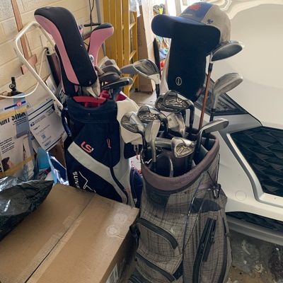 Sale Photo Thumbnail #54: Two golf bags filled with assorted clubs including irons and woods, accompanied by headcovers, displayed in a garage.