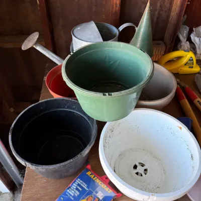 Sale Photo Thumbnail #42: Collection of assorted plastic plant pots alongside a metal watering can and a vintage packaged raincoat.