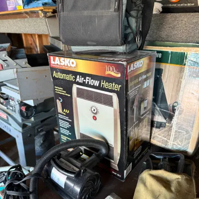Sale Photo Thumbnail #37: Boxed Lasko Automatic Air-Flow Heater, model 5812, alongside a small electric air pump, a California Innovations soft cooler bag, and various camping gear.