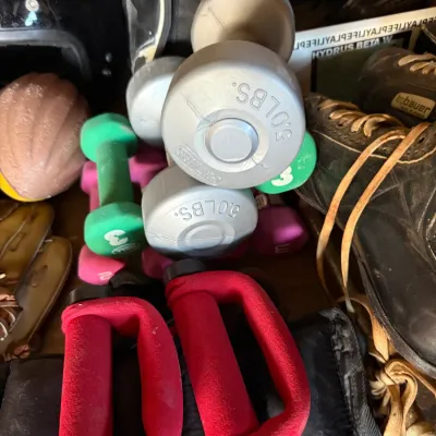 Sale Photo Thumbnail #35: Collection of vintage sports and fitness gear, including 5 lb and 3 lb dumbbells, red push-up handles, a black motorcycle helmet, and ice skates.
