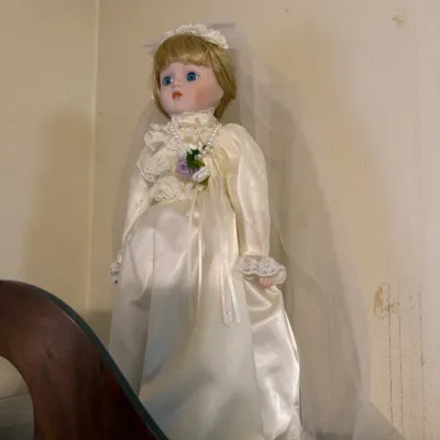 Vintage porcelain bride doll featuring blonde hair, blue eyes, a satin wedding gown with lace trim, and a full veil.
