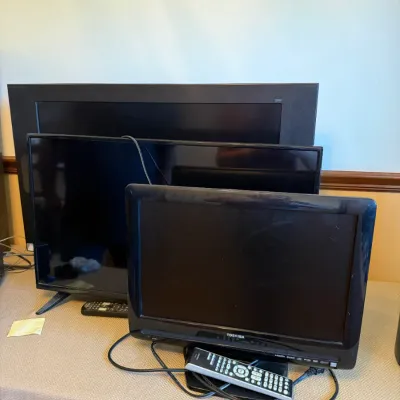 Group of three flat-screen LCD televisions in varying sizes, including a small Toshiba model with its original remote control.