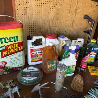 Sale Photo Thumbnail #43: Collection of lawn and garden care supplies including Preen weed preventer, various pest sprays, lawn tools, and gardening gloves.