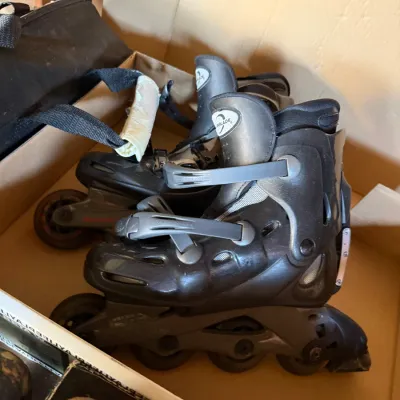 Sale Photo Thumbnail #34: Pair of Rollerblade brand inline skates in black and grey, stored inside a cardboard box.