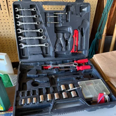 Molded black plastic tool case containing an incomplete set of hand tools, including combination wrenches, sockets, screwdrivers, and...
