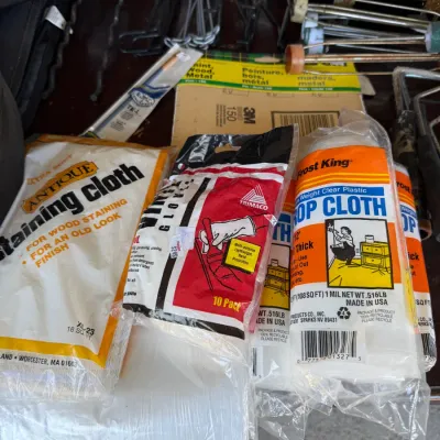 Assortment of painting and wood finishing supplies, including Frost King plastic drop cloths, Trimaco gloves, Antique staining cloth,...