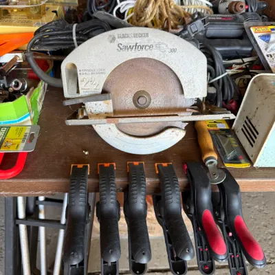 Vintage Black & Decker Sawforce 300 circular saw showing surface rust, displayed alongside six spring clamps and various workshop...