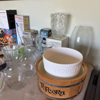 Collection of glass vases and tabletop items, including a white ceramic popcorn bowl nested inside a vintage wooden popcorn bucket.