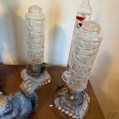 Pair of vintage woven pattern clear glass boudoir lamps alongside a glass Galileo thermometer and a metal squirrel figurine.