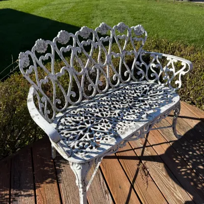 Sale Photo Thumbnail #45: Vintage painted white cast aluminum or iron garden bench featuring an ornate scrollwork back and pierced seat pattern, showing light weathering consistent with age.