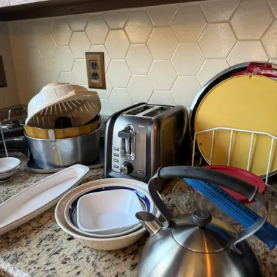 Selection of kitchen small appliances and cookware, including a stainless steel Oster toaster, Cuisinart tea kettle, plastic salad...