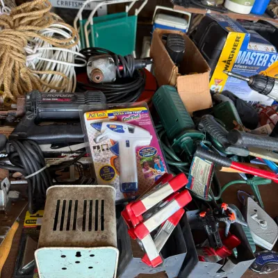 An assortment of workshop tools and hardware including an Ad Tech glue gun in original packaging, spring clamps, power tools, and coiled...