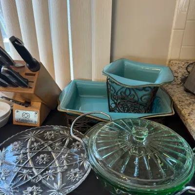 Collection of kitchen and serving items including turquoise ceramic dishes in wrought iron holders, a green glass covered casserole in a...