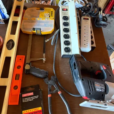 Sale Photo Thumbnail #40: Assortment of workshop tools and hardware including a Skil jigsaw, power strips, DeWalt bit organizer, levels, a hand saw, and pliers.
