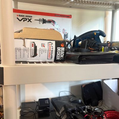 Sale Photo Thumbnail #35: Black & Decker power tools, lithium batteries, and assorted electronics arranged on plastic shelving units.