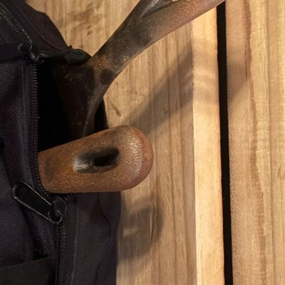 Sale Photo Thumbnail #52: Two vintage cast iron skillet handles peeking out from a black fabric bag, showing surface rust and patina.