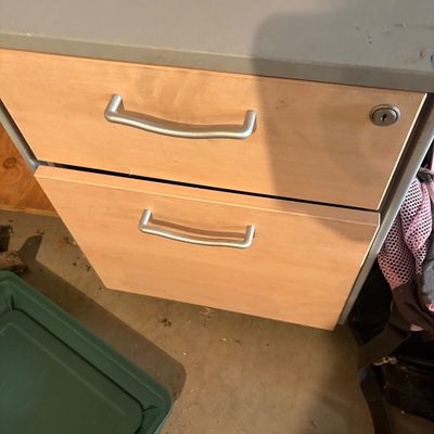 Sale Photo Thumbnail #113: Two-drawer office filing cabinet with light wood front panels and silver metal handles, topped with an Earl Weaver Baseball v1.5 code wheel.