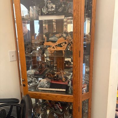 Sale Photo Thumbnail #24: Oak corner curio cabinet filled with a collection of miniature die-cast, wooden, and metal motorcycle display models.