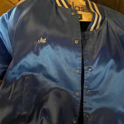 Sale Photo Thumbnail #119: Vintage blue satin bomber jacket with snap buttons, striped ribbed collar, and embroidered name "Jut" on the chest.