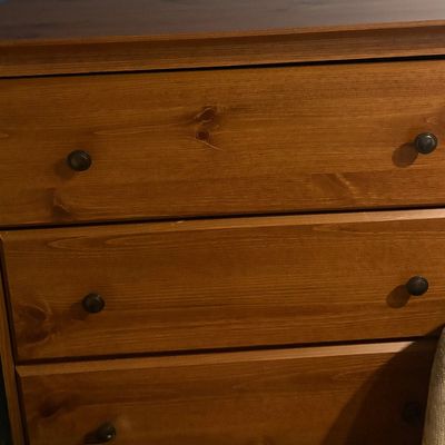 Sale Photo Thumbnail #23: Traditional stained pine three-drawer chest featuring round dark metal knobs and visible wood grain.