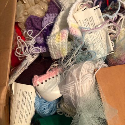 Sale Photo Thumbnail #47: Cardboard box filled with assortment of knitting and crochet supplies, including colorful yarn skeins, finished crochet pieces, netting, and instruction labels.