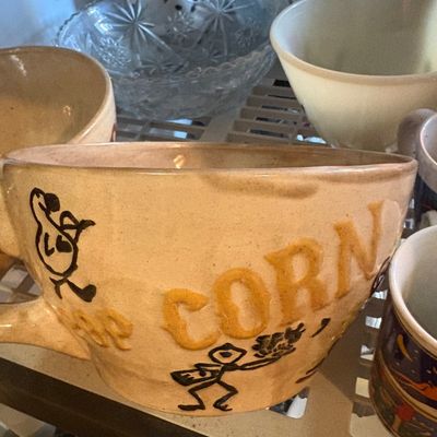 Sale Photo Thumbnail #87: Vintage pottery popcorn bowl with embossed lettering and whimsical stick figure illustrations, displayed alongside assorted glassware and ceramics.