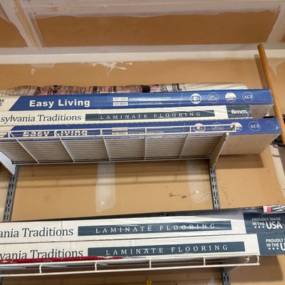 Sale Photo Thumbnail #36: Multiple boxed sets of Empire Today Pennsylvania Traditions 8mm laminate flooring stored on wire garage shelving.
