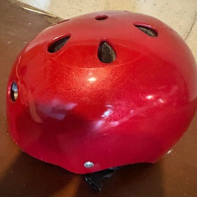 Sale Photo Thumbnail #103: Glossy red metallic sports or multi-impact helmet featuring multiple ventilation holes and an adjustable chin strap.