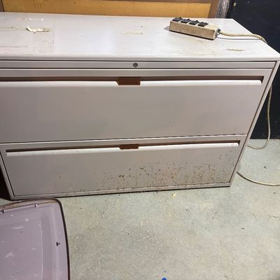 Sale Photo Thumbnail #101: Beige two-drawer metal lateral filing cabinet showing visible wear, surface scuffs, and dirt, complete with recessed drawer pulls.