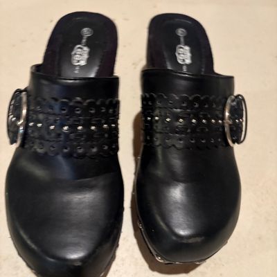Sale Photo Thumbnail #128: Pair of women's black leather slip-on clogs by Route 66, featuring silver-tone buckle accents, laser-cut detailing, and stud embellishments.
