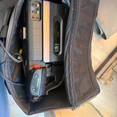 Sale Photo Thumbnail #62: Vintage Sharp VHS camcorder stored in a soft black padded carrying case with attached cords.